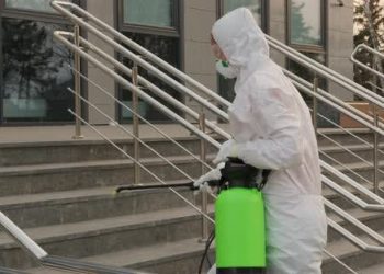 Worker In A Protective Suit Disinfects Surfaces From Coronavirus. Antibacterial Sanitary Measures On